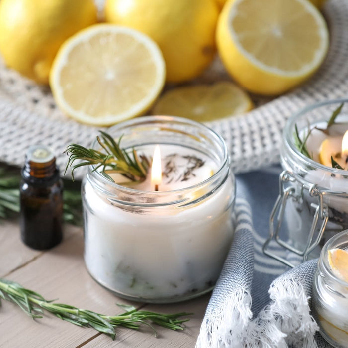 Natural mosquito repellent candles with lemon, rosemary, and essential oils on a summer outdoor hosting setup